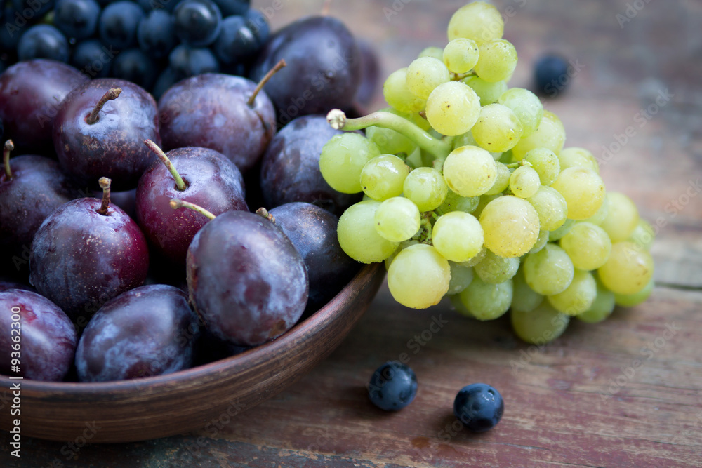 Fototapeta premium Plums and grapes on the wooden table