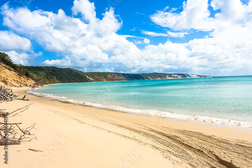 Colorful sand cliffs with white sandy beach containing four wheel drive tracks. Rainbow Beach, Queensland, Australia.
