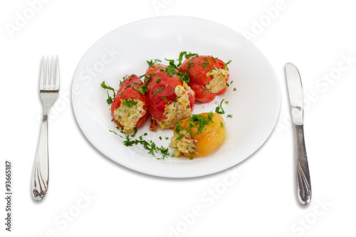 Stuffed bell peppers on a white dish, fork and knife