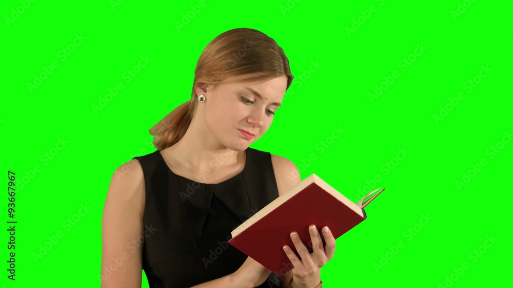 Young beautiful girl reading a book on laptop on a Green Screen Young beautiful girl reading a book on laptop on a Green Screen