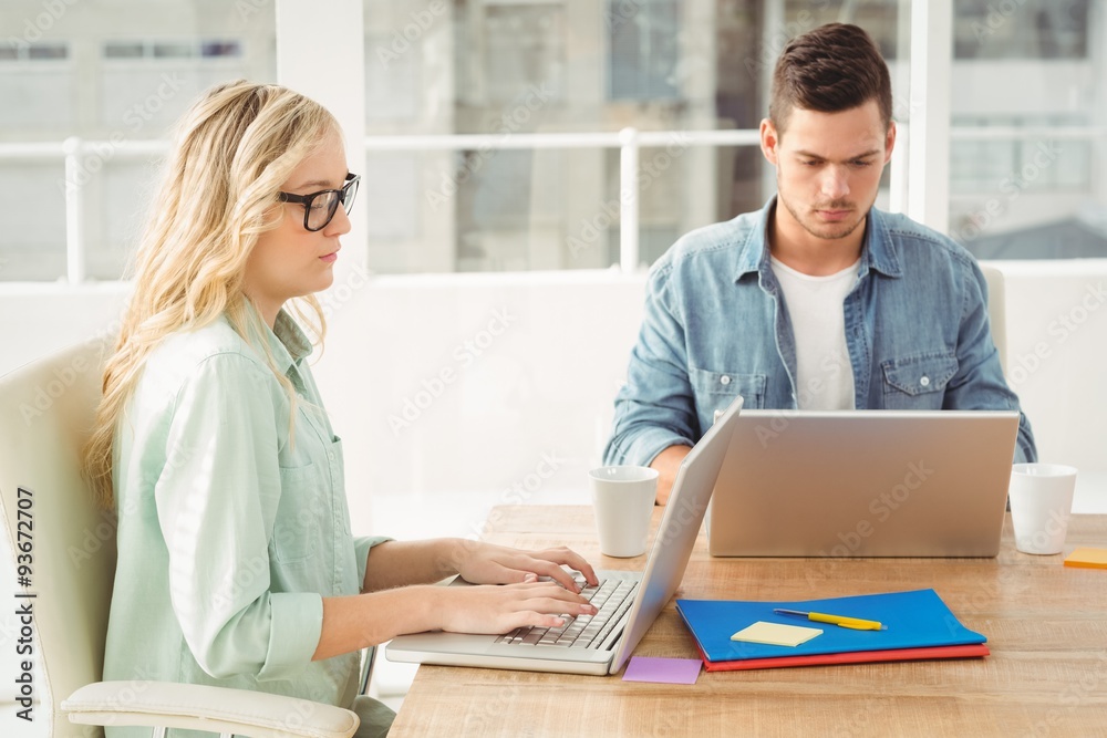 Serious people working on laptop while sitting at desk Serious people working on laptop while sitting at desk