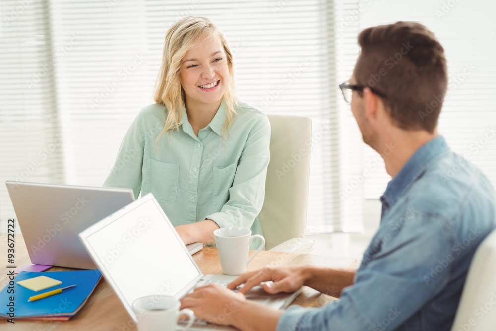 Smiling woman looking at man while sitting on chair Smiling woman looking at man while sitting on chair