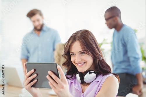 Smiling woman with headphones while using digital tablet 