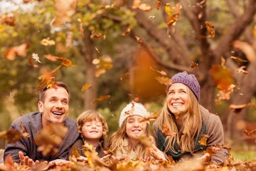 Smiling young family throwing leaves around