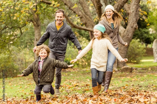Smiling young family running into leaves