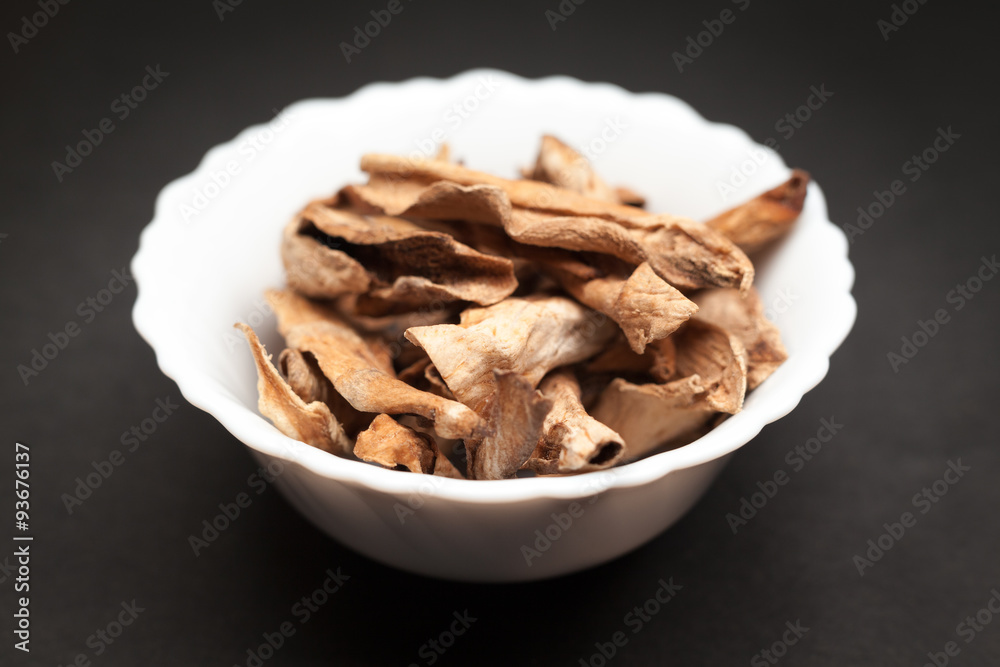 Organic Sour dried mango or Aamchur or Amchoor (Mangifera indica) in white ceramic bowl on dark background. Organic Sour dried mango or Aamchur or Amchoor (Mangifera indica) in white ceramic bowl on dark background.