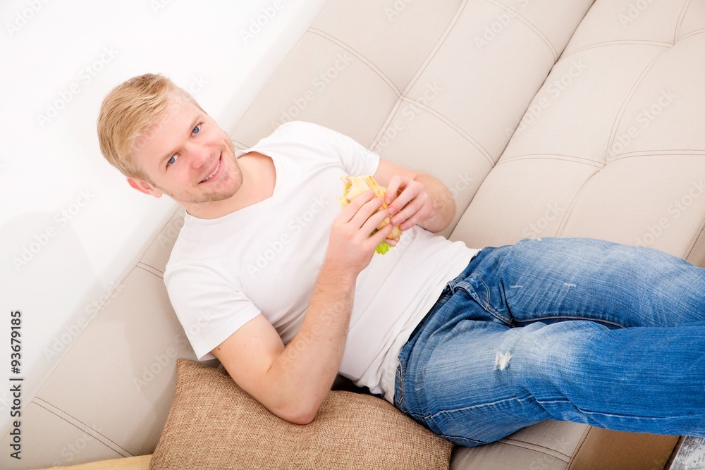 Young man eating a sandwich at home Young man eating a sandwich at home