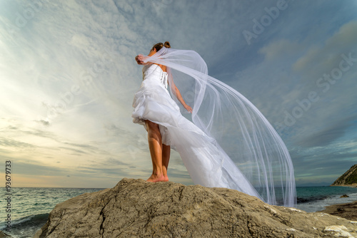 YOung bride by the sea at sunset