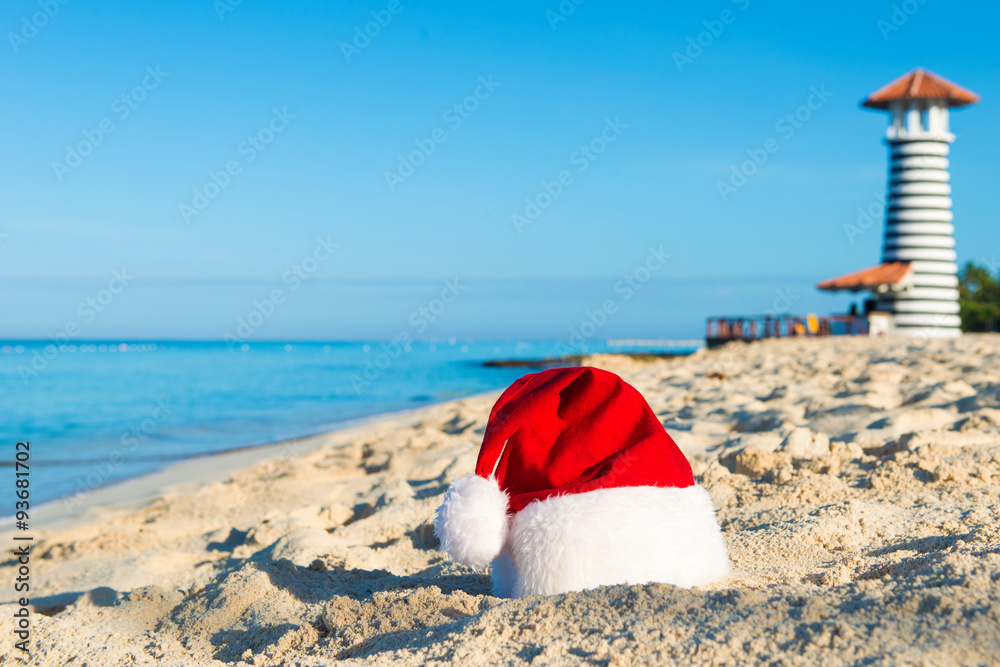Happy New Year holidays at Sea. Santa hat on sandy beach - christmas holiday concept Happy New Year holidays at Sea. Santa hat on sandy beach - christmas holiday concept