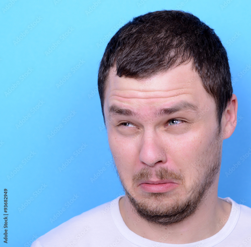 Obraz premium Portrait of man with dusgusted gesture against blue background