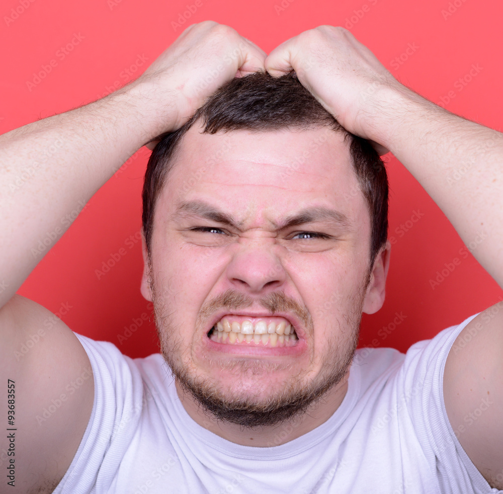 Obraz premium Portrait of angry man screaming and pulling hair against red bac