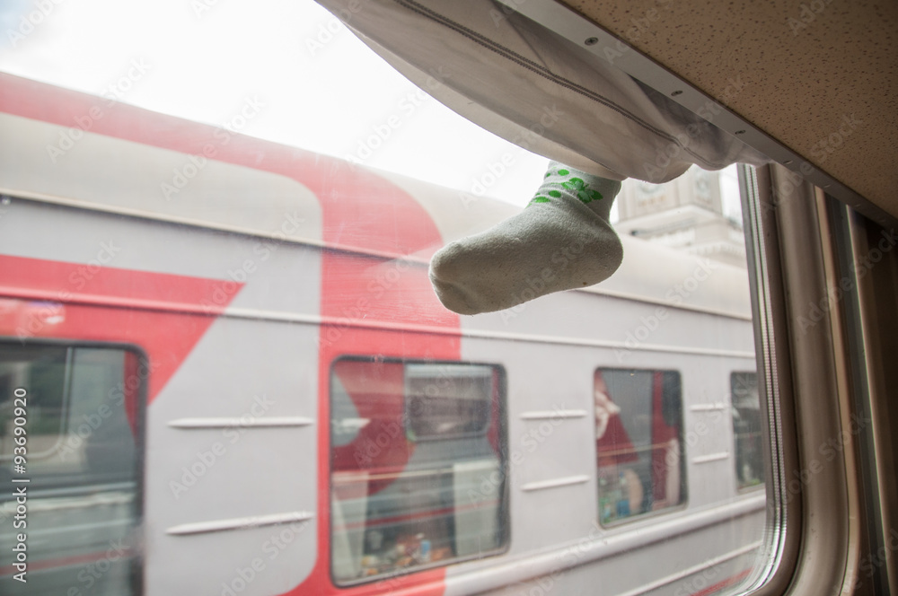 Fototapeta premium Childrens leg hanging from the side of the top shelf second-class train carriage