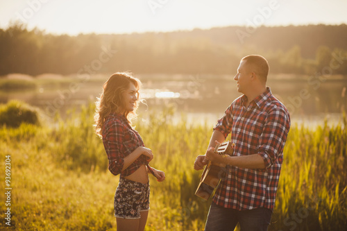 cheerful and carefree couple with a guitar outdoors.