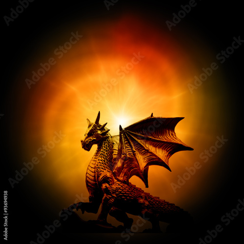 a statue of dragon over orange mysterious backround