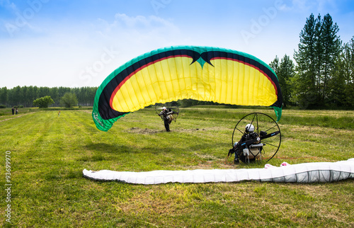 man with motorized paraglider takes off from a field