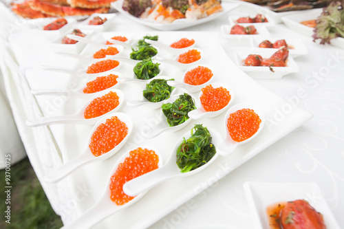 red caviar close-up in white spoons on banquet