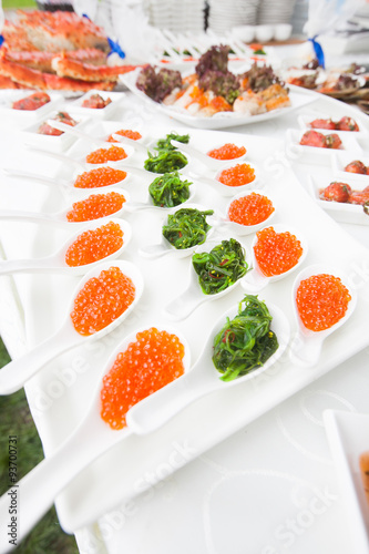 red caviar close-up in white spoons on banquet