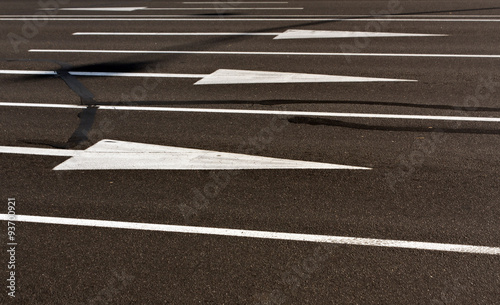 White arrows and lines on cracked asphalt surface.