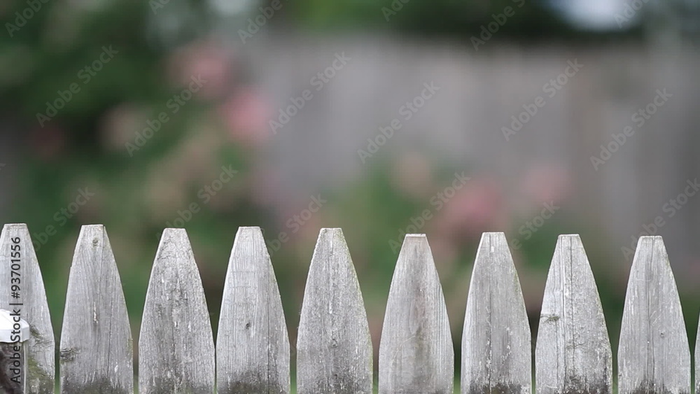 Old Fence Dolly Left to Right. HD 1080p dolly shot of the tip of a picket fence from left to right. slow motion. shallow depth of field. flowers in background.
