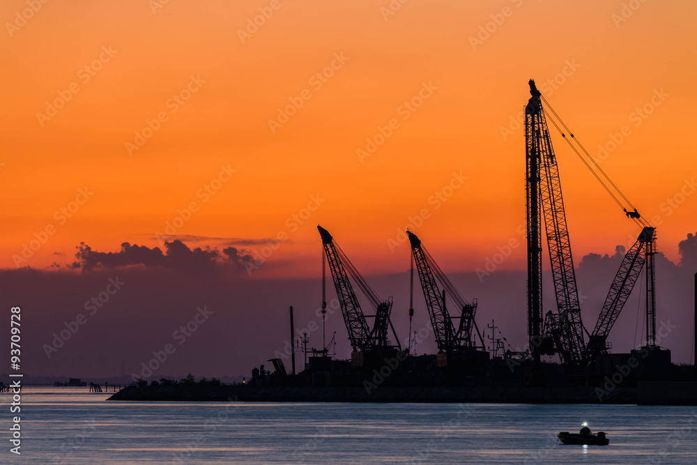 Chioggia, le gru del Mose al tramonto con un pescatore in barca