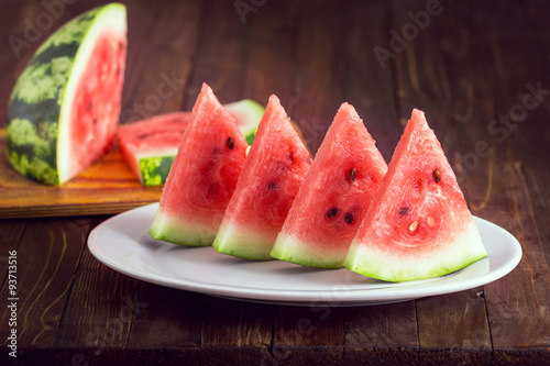 slices of watermelon in a white plate on a wooden background