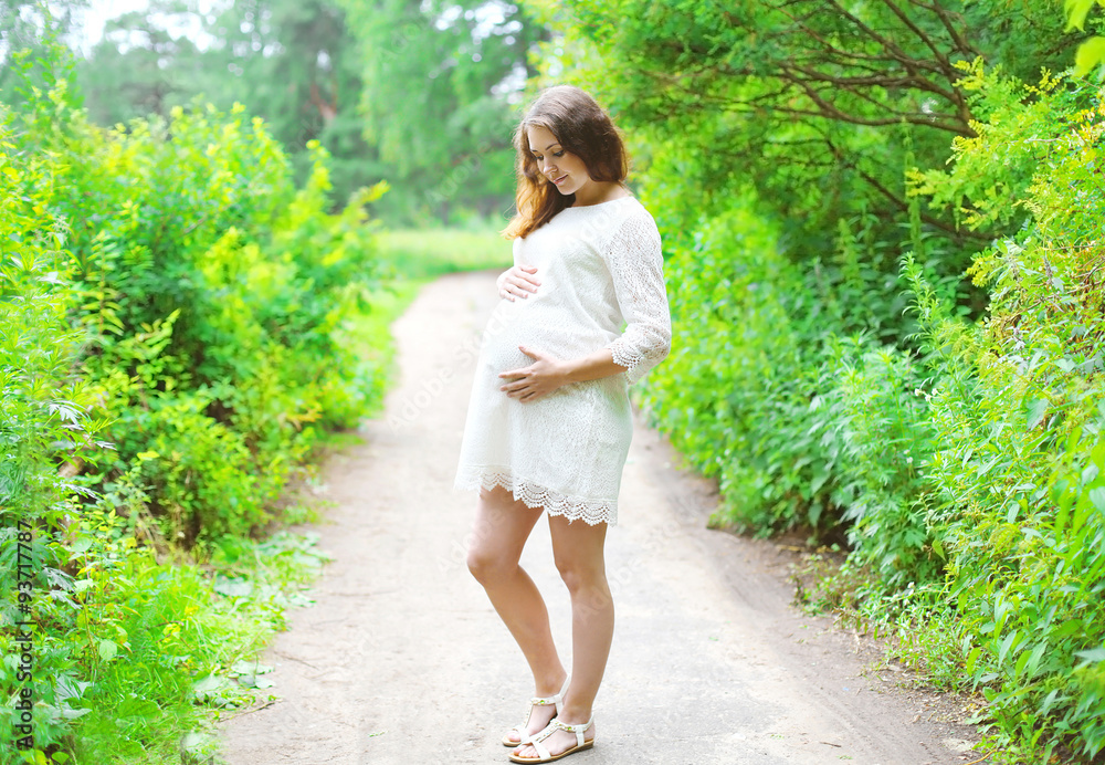 Beautiful young pregnant woman in white dress outdoors on nature Beautiful young pregnant woman in white dress outdoors on nature