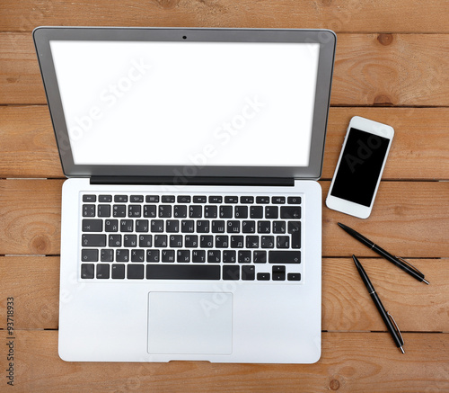 Pens and smart phone near open notebook on wooden background, top view