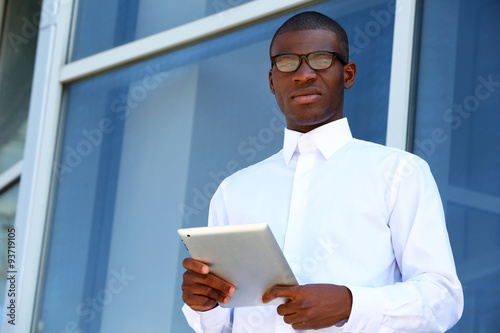 Handsome African American businessman with digital tablet near business centre