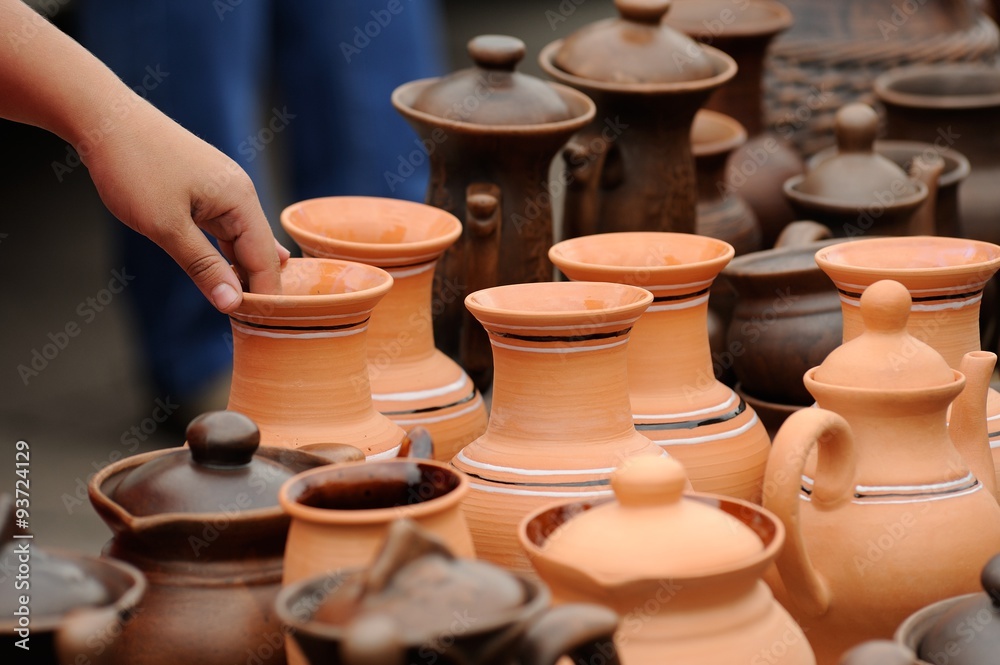 Row of new handmade pottery with woman's hand
