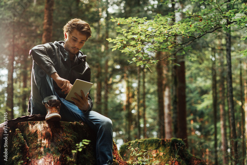 Young man using a digital tablet in the woods
