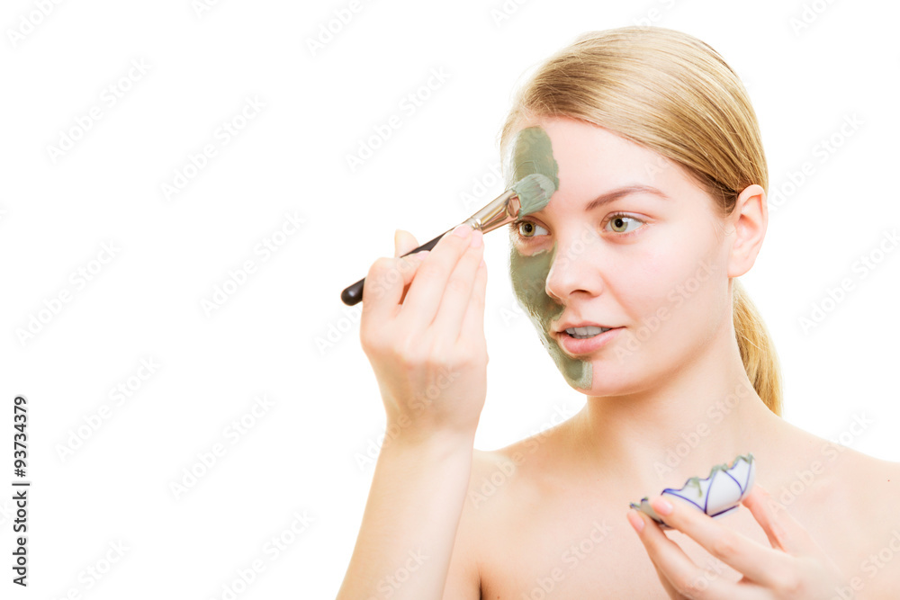 Girl applying facial clay mask to her face Girl applying facial clay mask to her face
