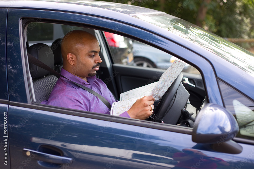 man sitting in his car reading a map