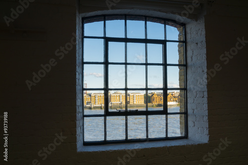 Across River Thames through old wahrehose window, Wapping, London buildings