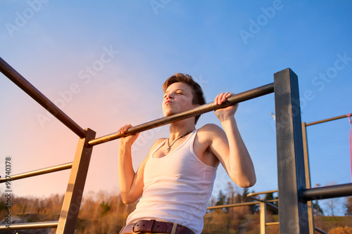 teen training on horizontal bar outdoors