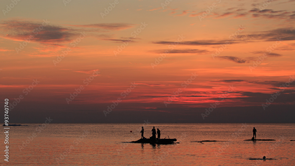 Ocean landscape at sunset. Silhouettes of fishermen.