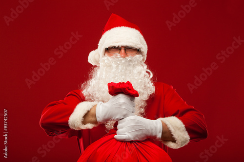 santa claus with big bag on shoulder glasses red background