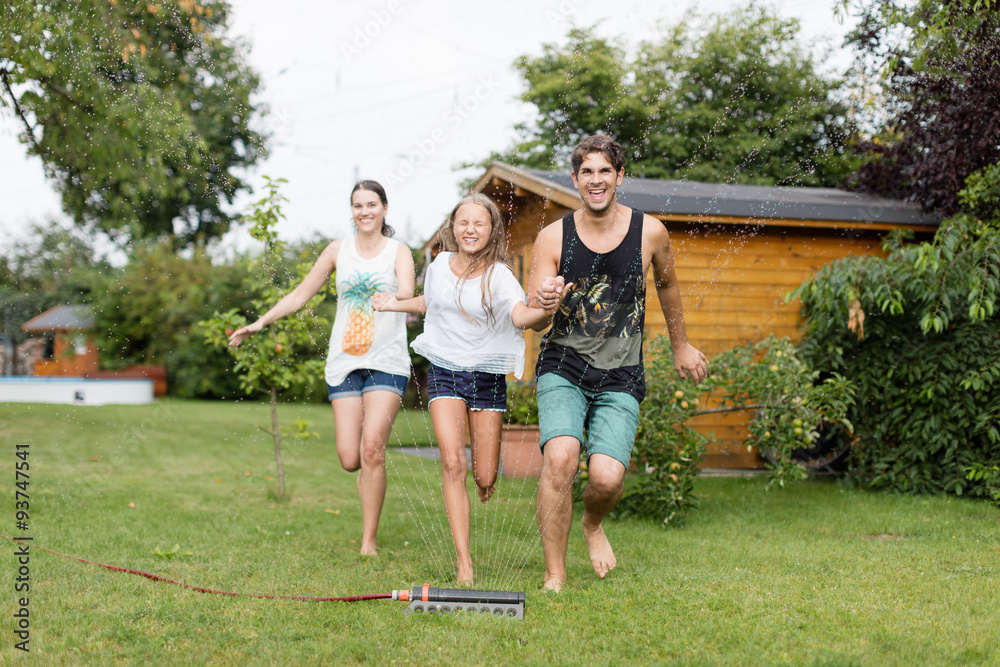 Fototapeta premium Familie läuft über einen Wassersprenger