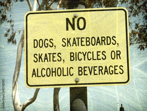 aged and worn vintage photo of no skateboards or dogs sign
