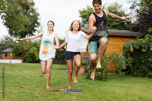 Familie läuft über einen Wassersprenger photo