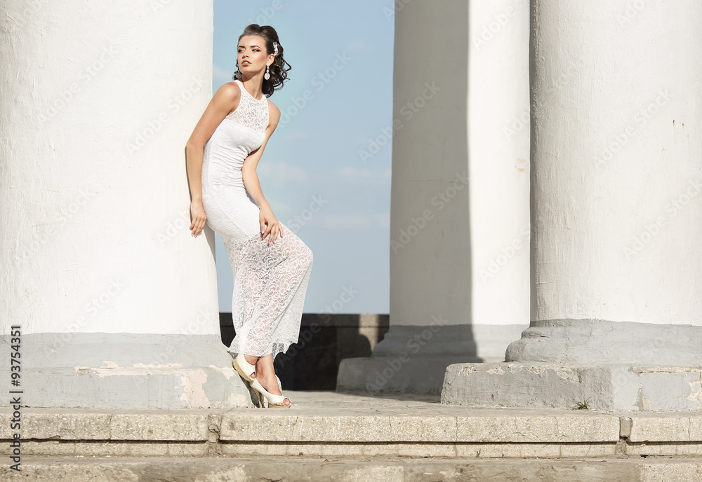 Girl, model, bride standing at the column and looks into the dis