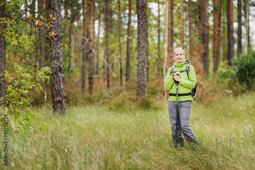 woman with hiking equipment walking in forest © kaninstudio