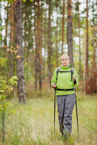 woman with hiking equipment walking in forest © kaninstudio