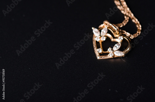 Golden heart with necklace chain on black background.