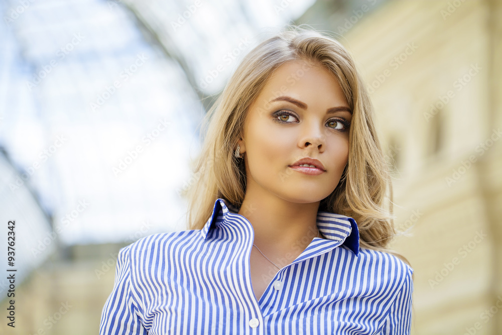 Portrait of a beautiful blonde in a blue striped shirt