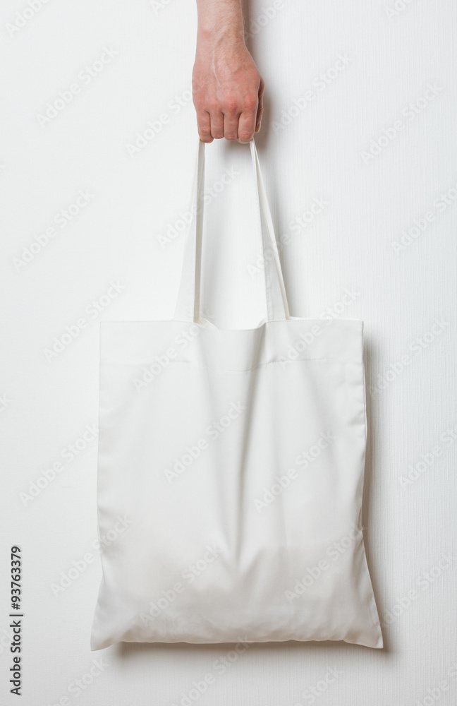 Male hand holding white textile bag Male hand holding white textile bag