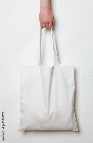 Male hand holding white textile bag