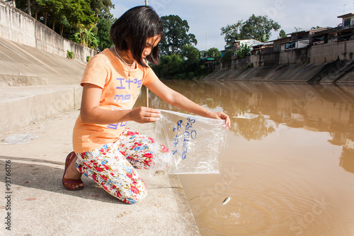 cute asian girl release fish into the canal photo