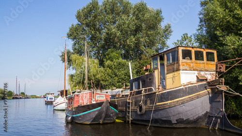 A big old barge, a sailboat and a cabin boat on the side next to