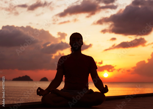 man doing yoga at sunset