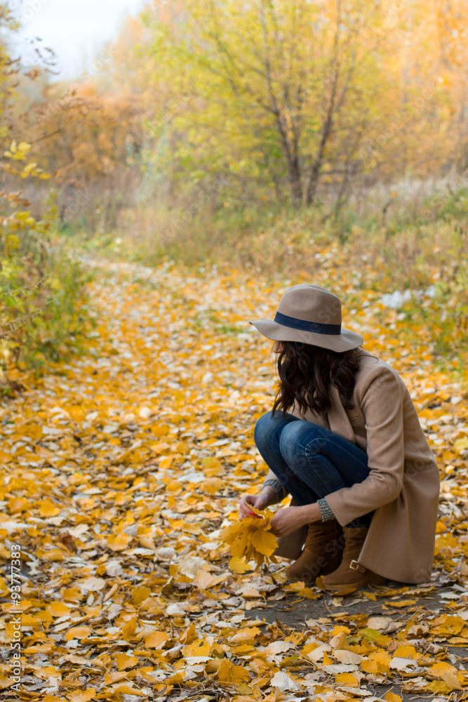 girl in the coat collects leaves in the forest girl in the coat collects leaves in the forest